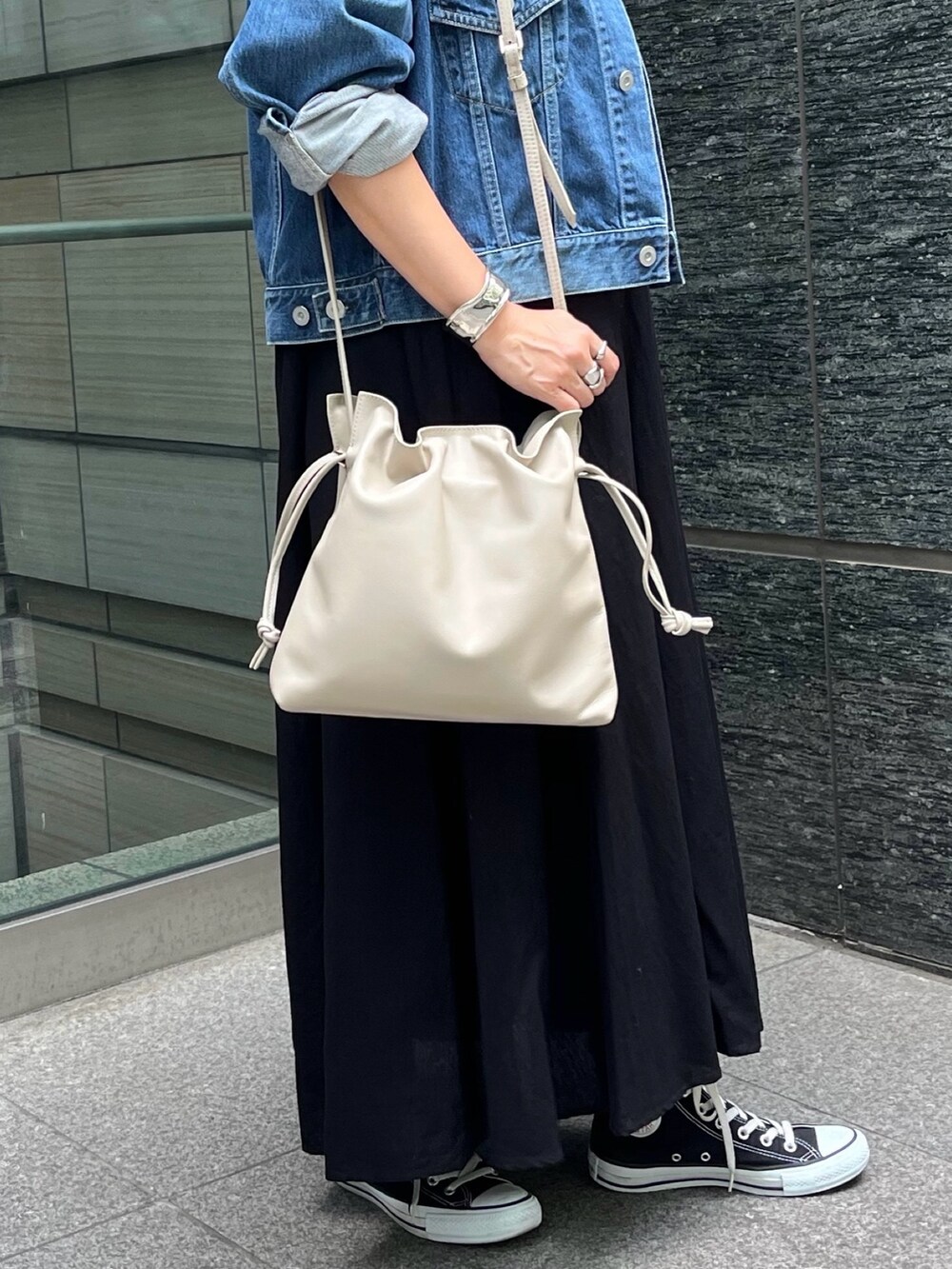 ベージュ系のショルダーバッグ、ブラック系のワンピース、シルバー系のバングル/リストバンドを着用したレディースの秋コーディネートの4枚目の写真