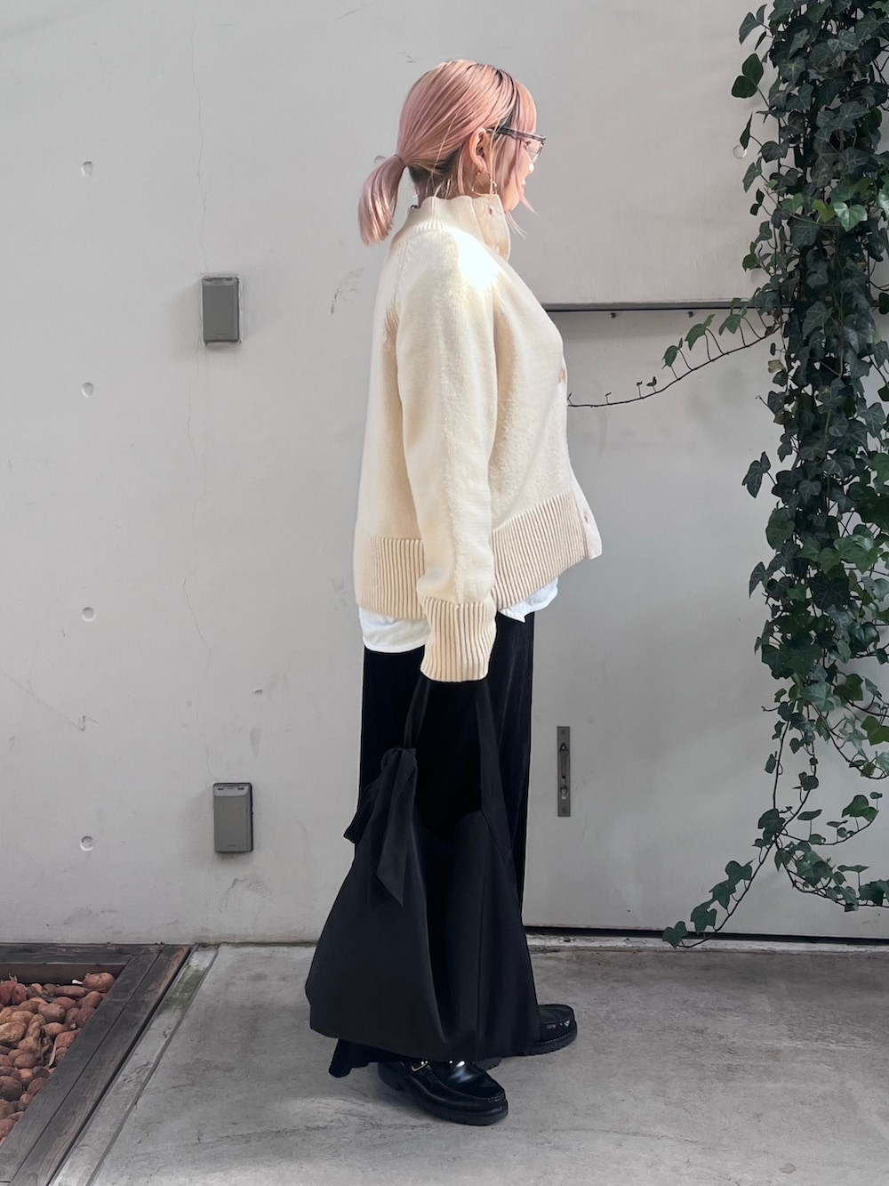 ホワイト系のニット/セーター、ホワイト系のTシャツ/カットソー、ブラック系のトートバッグを着用したレディースの冬コーディネートの2枚目の写真