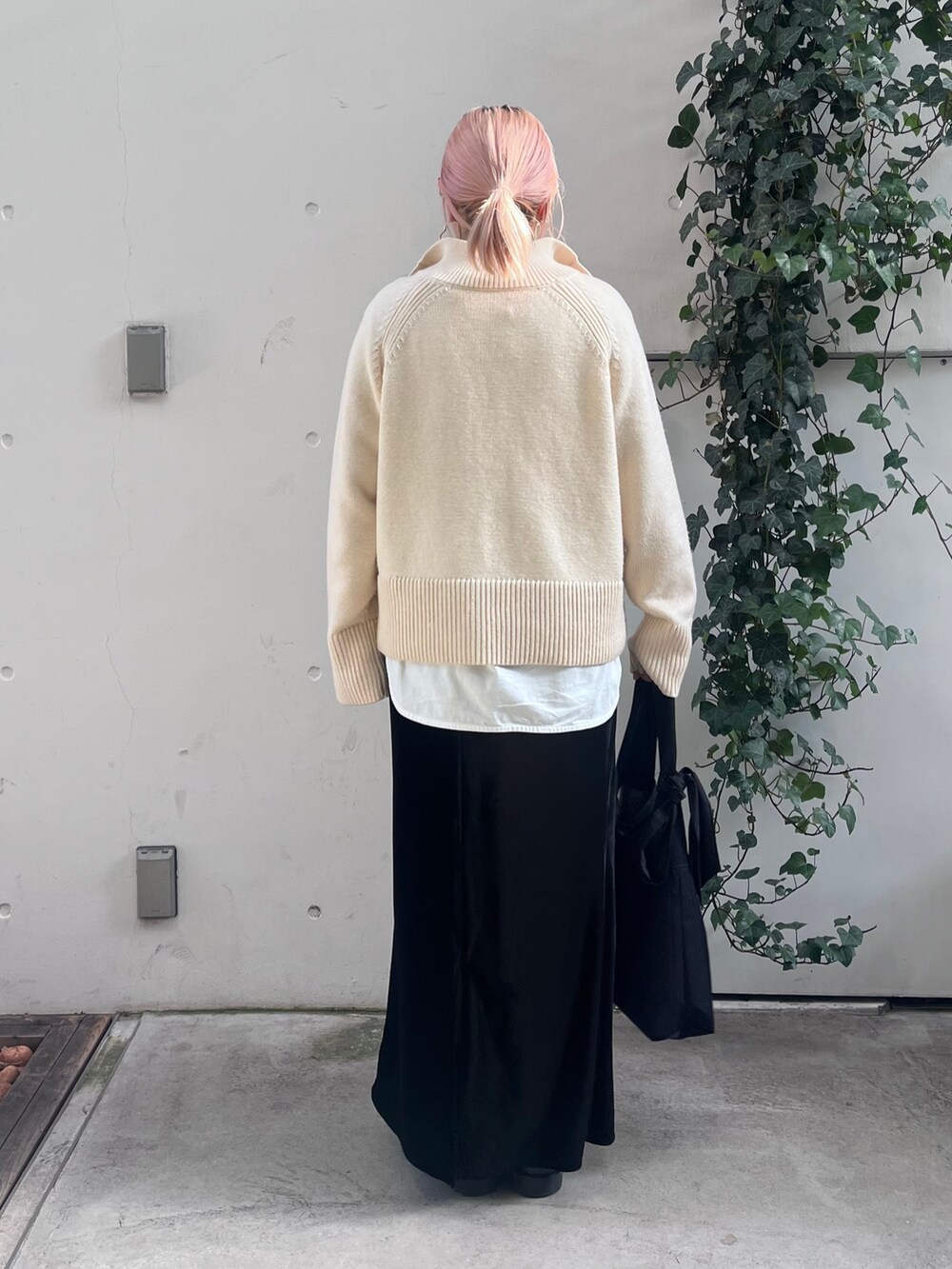 ホワイト系のニット/セーター、ホワイト系のTシャツ/カットソー、ブラック系のトートバッグを着用したレディースの冬コーディネートの3枚目の写真