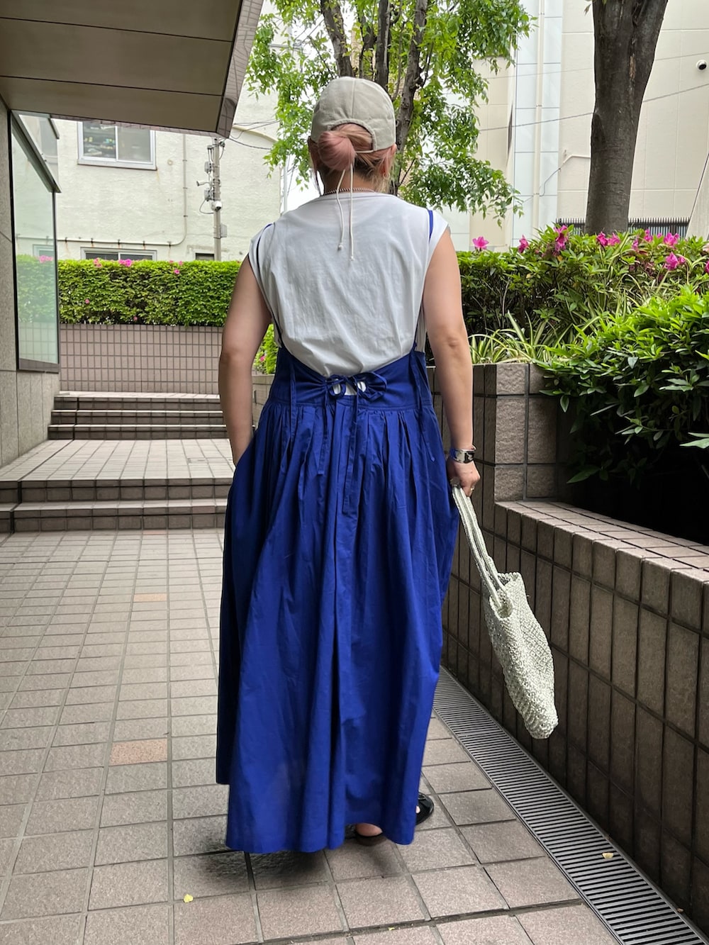 ブルー系のワンピース、ゴールド系のかごバッグ、ブラック系のサンダルを着用したレディースの夏コーディネートの4枚目の写真