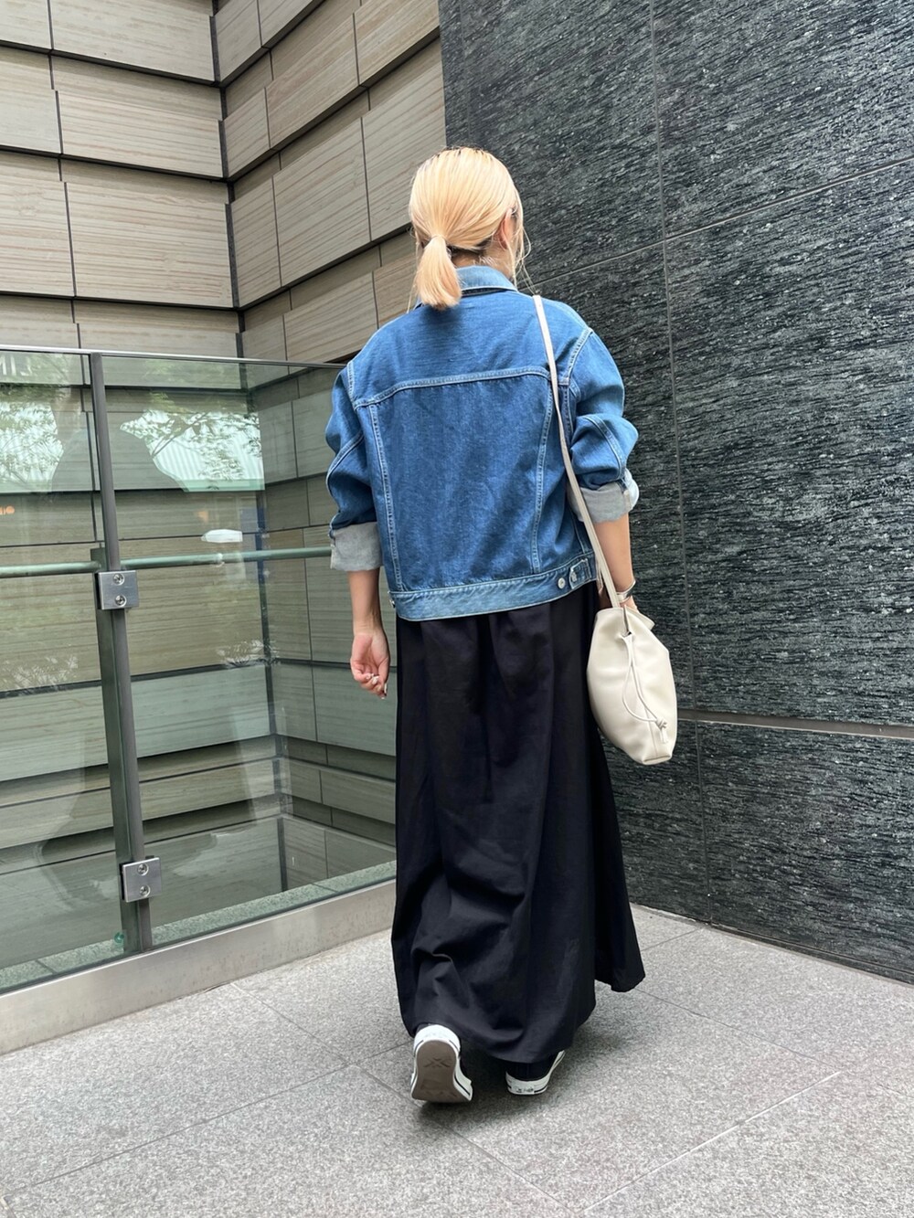 ベージュ系のショルダーバッグ、ブラック系のワンピース、シルバー系のバングル/リストバンドを着用したレディースの秋コーディネートの3枚目の写真