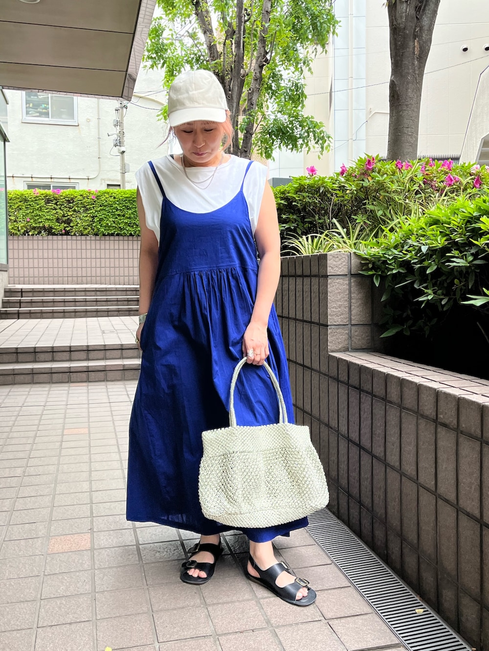 ブルー系のワンピース、ゴールド系のかごバッグ、ブラック系のサンダルを着用したレディースの夏コーディネートの3枚目の写真