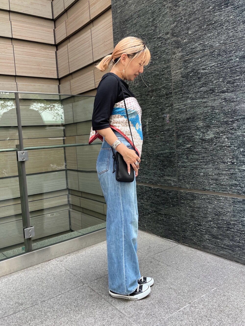 ブルー系のデニムパンツ、ブラック系のTシャツ/カットソー、ベージュ系のストール/ショールを着用したレディースの秋コーディネートの3枚目の写真