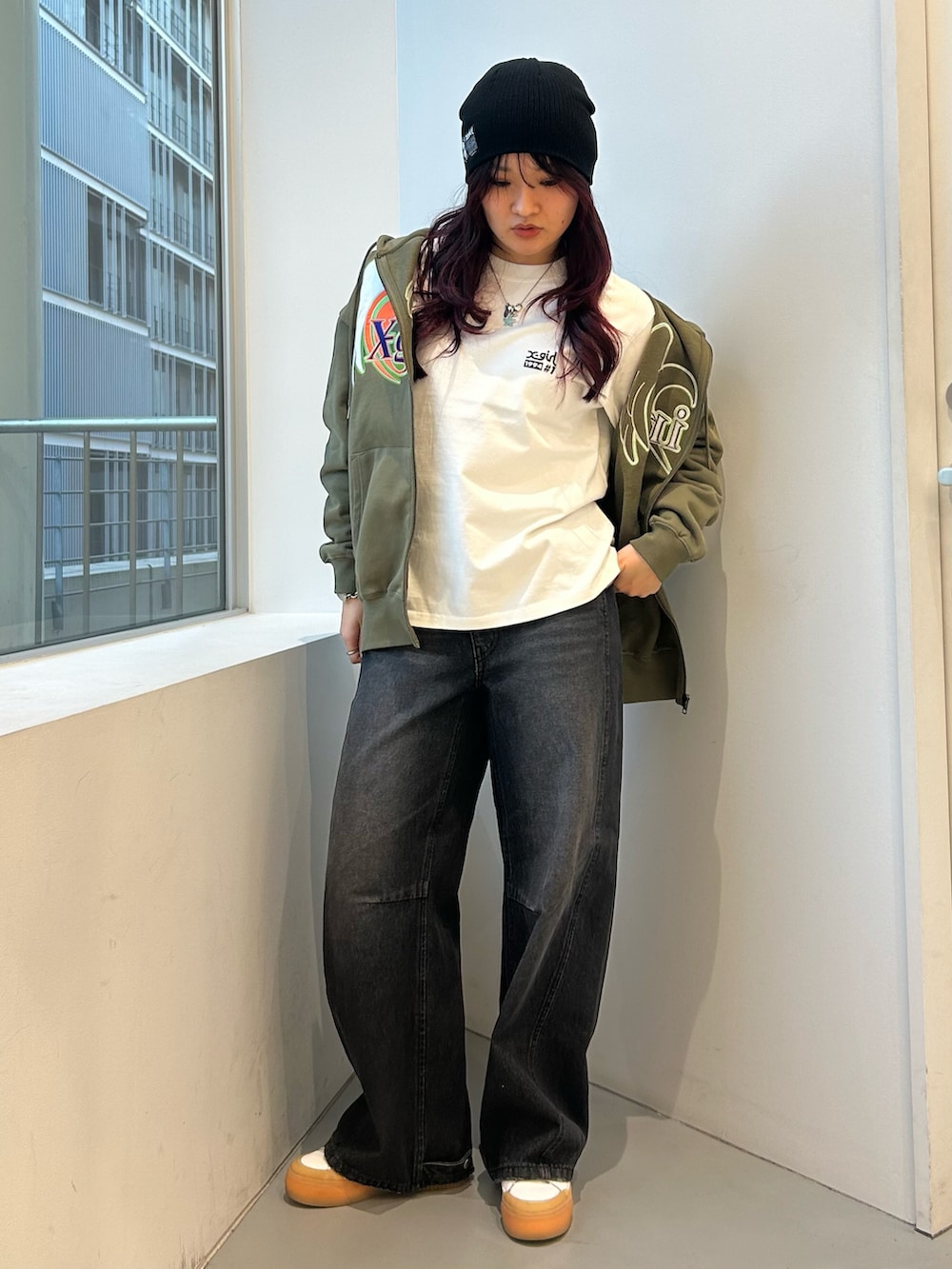 グリーン系のパーカー、ブラック系のデニムパンツ、ホワイト系のTシャツ/カットソーを着用したレディースの冬コーディネートの5枚目の写真