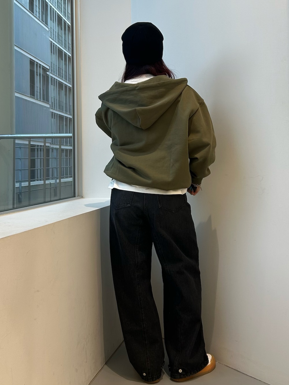 グリーン系のパーカー、ブラック系のデニムパンツ、ホワイト系のTシャツ/カットソーを着用したレディースの冬コーディネートの3枚目の写真