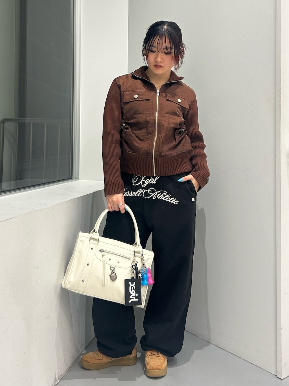 ブラウン系のブルゾン、ブラック系のスウェットパンツ、ホワイト系のショルダーバッグを着用したレディースの冬コーディネートの5枚目の写真