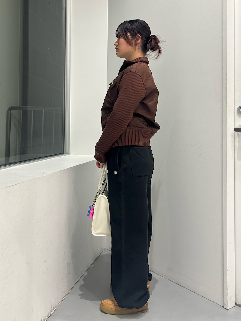 ブラウン系のブルゾン、ブラック系のスウェットパンツ、ホワイト系のショルダーバッグを着用したレディースの冬コーディネートの2枚目の写真