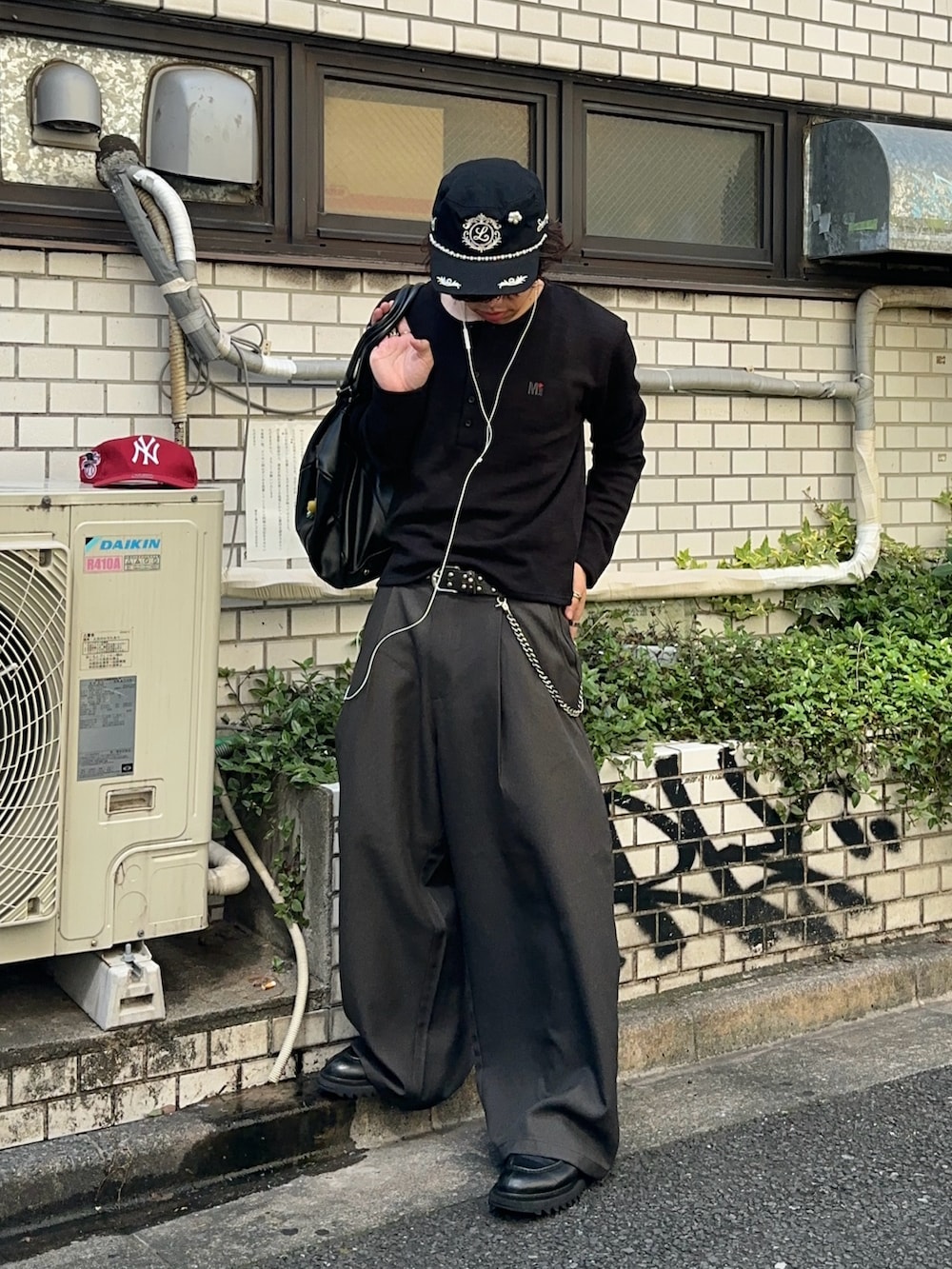 ブラック系のニット/セーター、グレー系のスラックス、ブラック系のモカシン/デッキシューズを着用したメンズの夏コーディネートの2枚目の写真