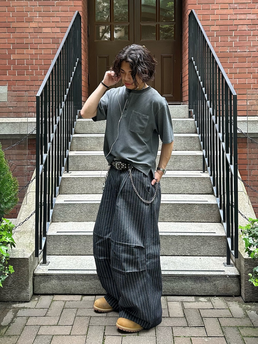 イエロー系のブーツ、ブラック系のTシャツ/カットソー、ブラック系のデニムパンツを着用したメンズの春コーディネートの2枚目の写真