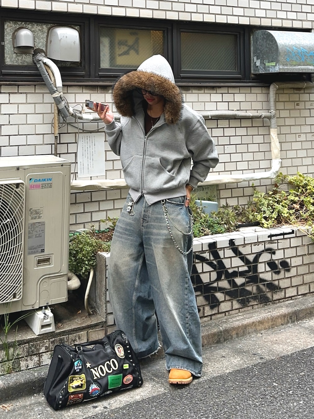 ブラック系のボストンバッグ、グレー系のパーカー、イエロー系のブーツを着用したメンズの秋コーディネートの2枚目の写真