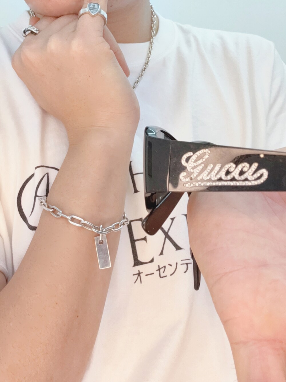 ベージュ系のクラッチバッグ、グレー系のスニーカー、ブラック系のサングラスを着用したメンズの秋コーディネートの3枚目の写真