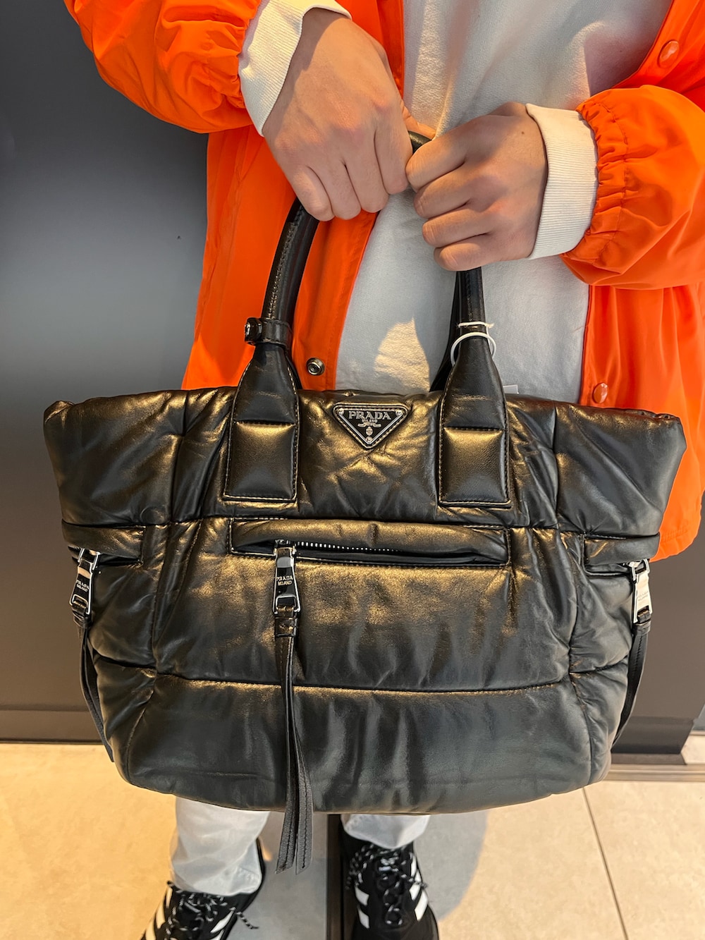 オレンジ系のナイロンジャケット、ホワイト系のスウェット、ホワイト系のデニムパンツを着用したメンズの秋コーディネートの3枚目の写真