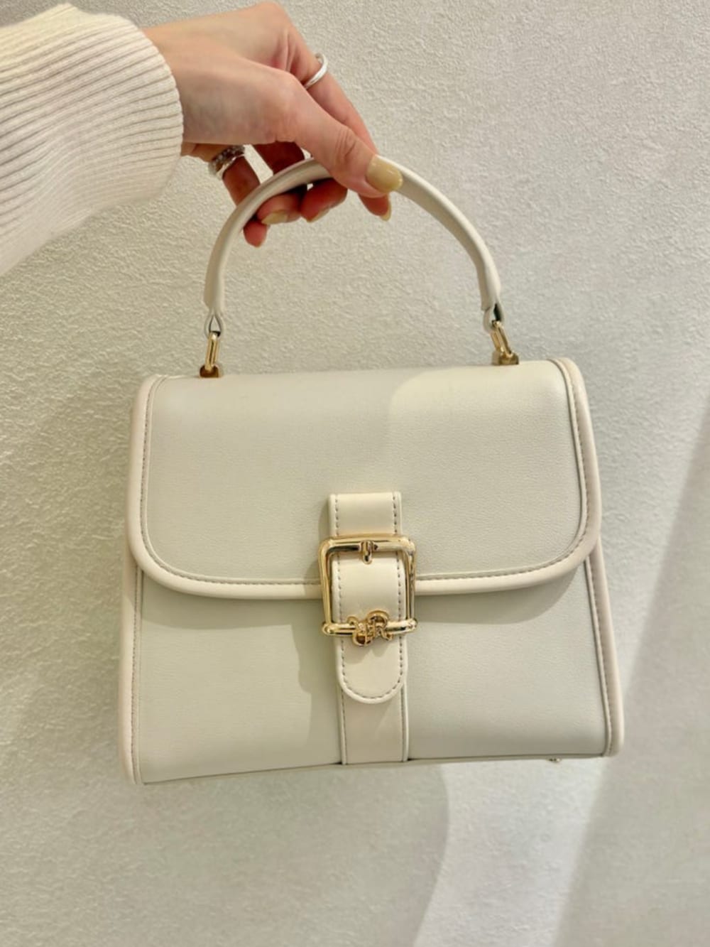 ベージュ系のワンピース、グレー系のテーラードジャケット、ホワイト系のハンドバッグを着用したレディースの春コーディネートの3枚目の写真