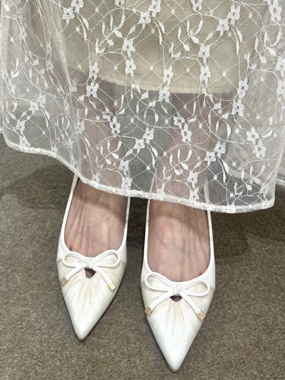 ホワイト系のハンドバッグ、ベージュ系のワンピース、ホワイト系のパンプスを着用したレディースの夏コーディネートの2枚目の写真