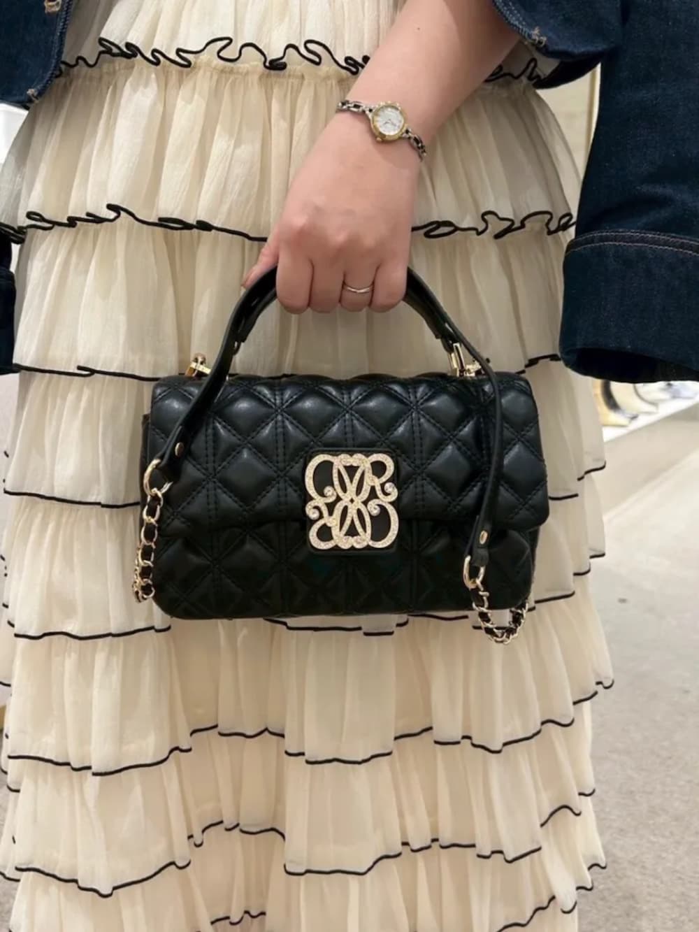 ブルー系のデニムジャケット、ブラック系のワンピース、ブラック系のショルダーバッグを着用したレディースの春コーディネートの3枚目の写真