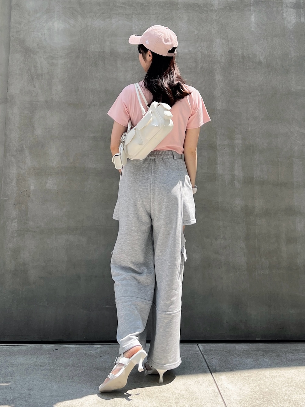 グレー系のカーゴパンツ、ピンク系のTシャツ/カットソー、ホワイト系のボストンバッグを着用したレディースの夏コーディネートの3枚目の写真