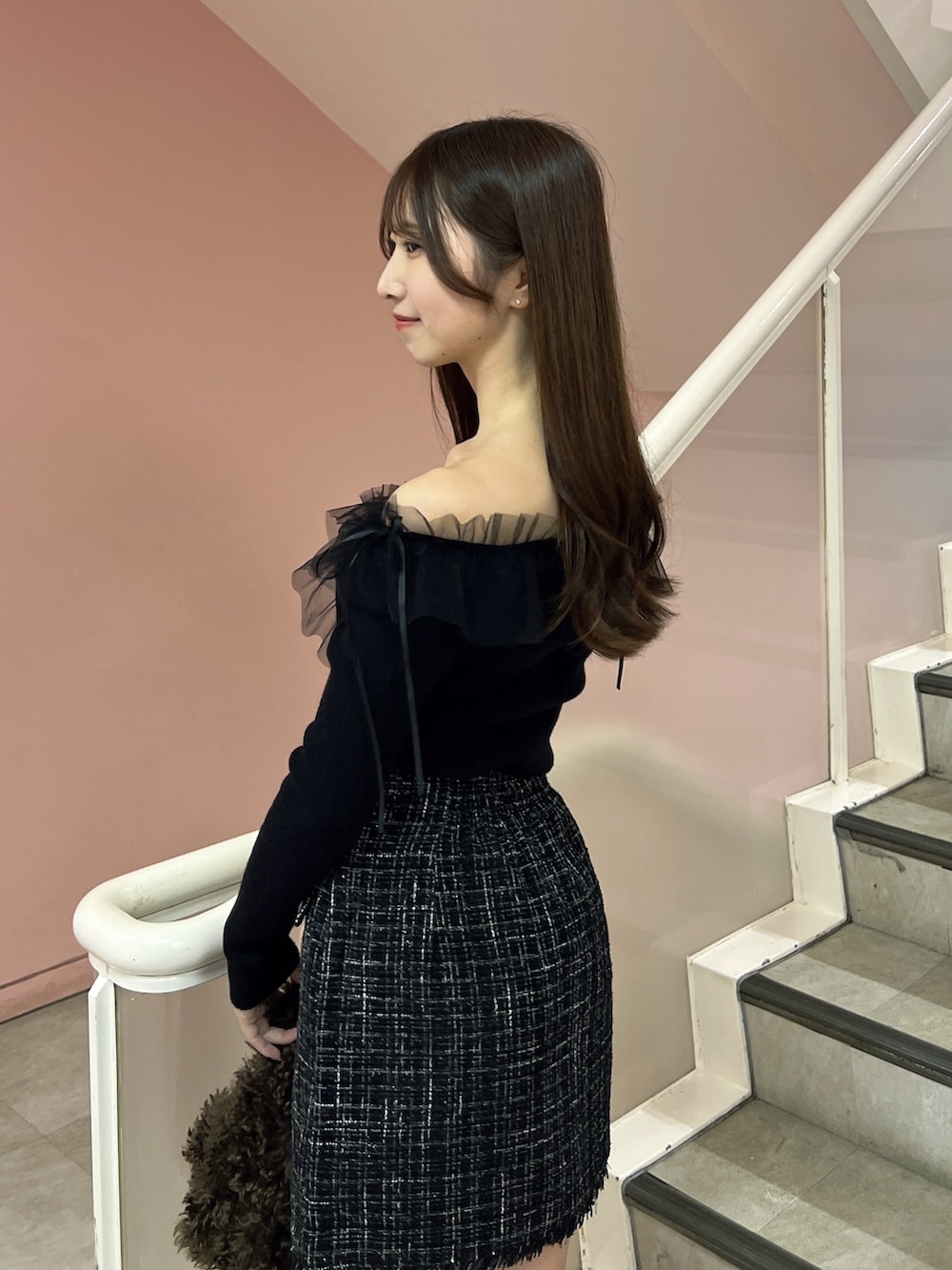 ブラック系のスカート、ブラック系のニット/セーター、ブラウン系のハンドバッグを着用したレディースの秋コーディネートの6枚目の写真