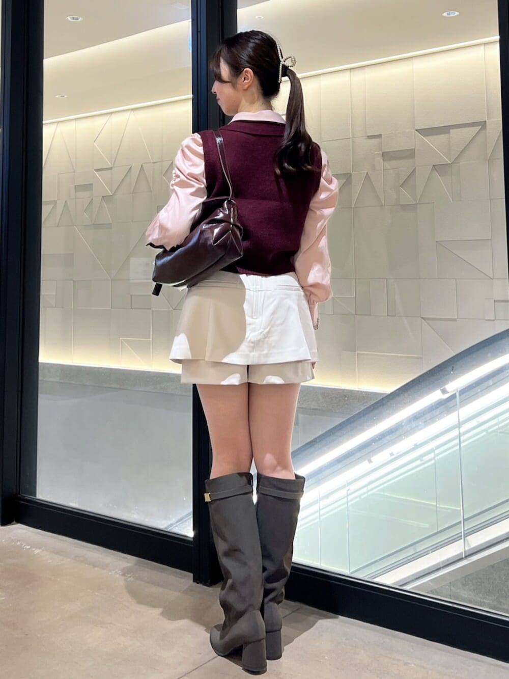 ブラウン系のブーツ、レッド系のハンドバッグ、ホワイト系のスカートを着用したレディースの秋コーディネートの3枚目の写真