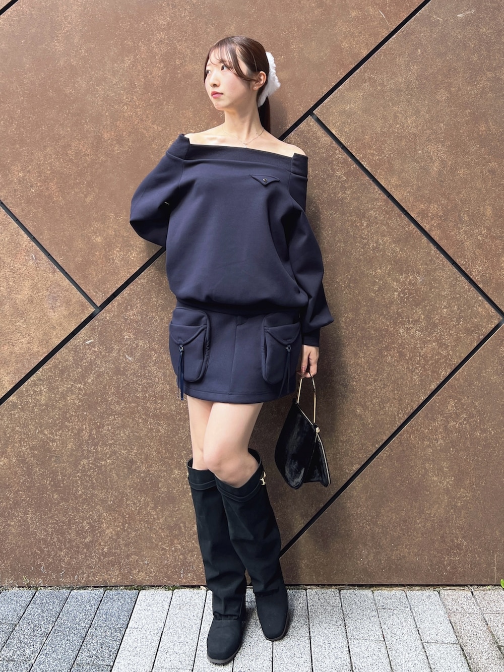 ブルー系のスウェット、ブルー系のスカート、ブラック系のハンドバッグを着用したレディースの秋コーディネートの2枚目の写真