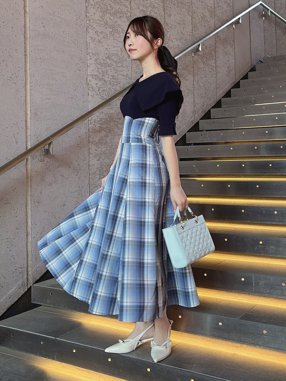 ブルー系のワンピース、ブルー系のハンドバッグ、ホワイト系のパンプスを着用したレディースの春コーディネートの3枚目の写真