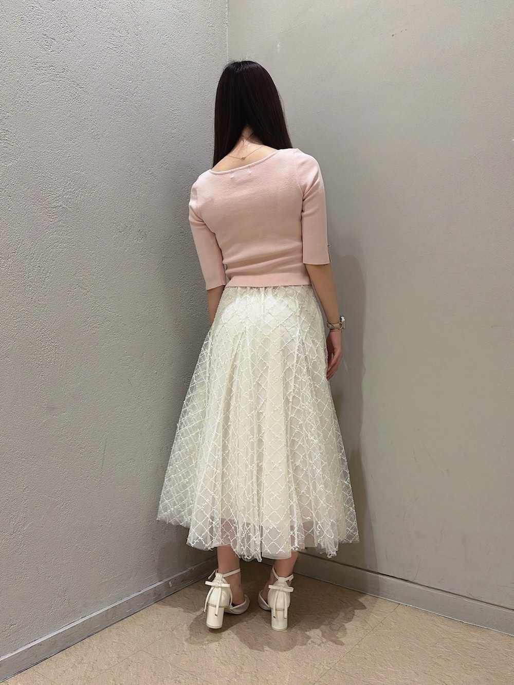 ホワイト系のパンプス、ホワイト系のハンドバッグ、ホワイト系のスカートを着用したレディースの夏コーディネートの4枚目の写真