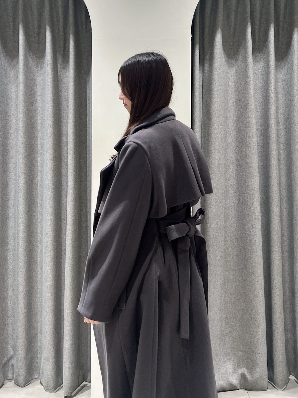 ブラウン系のトレンチコート、ブラウン系のブーツ、ホワイト系のスカートを着用したレディースの秋コーディネートの5枚目の写真