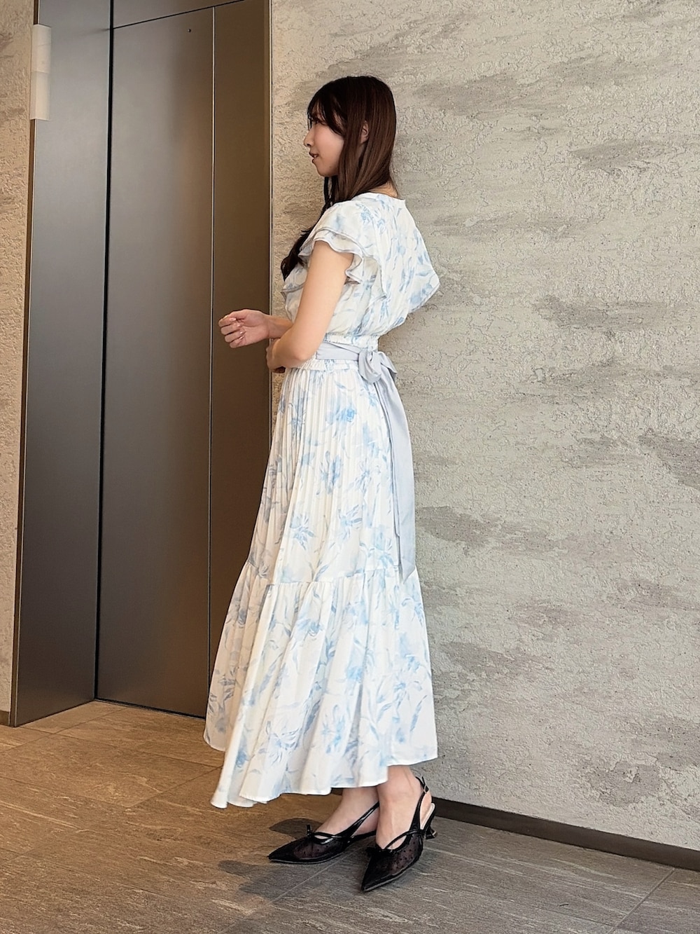 ブラック系のパンプス、ホワイト系のハンドバッグ、ブルー系のワンピースを着用したレディースの夏コーディネートの2枚目の写真