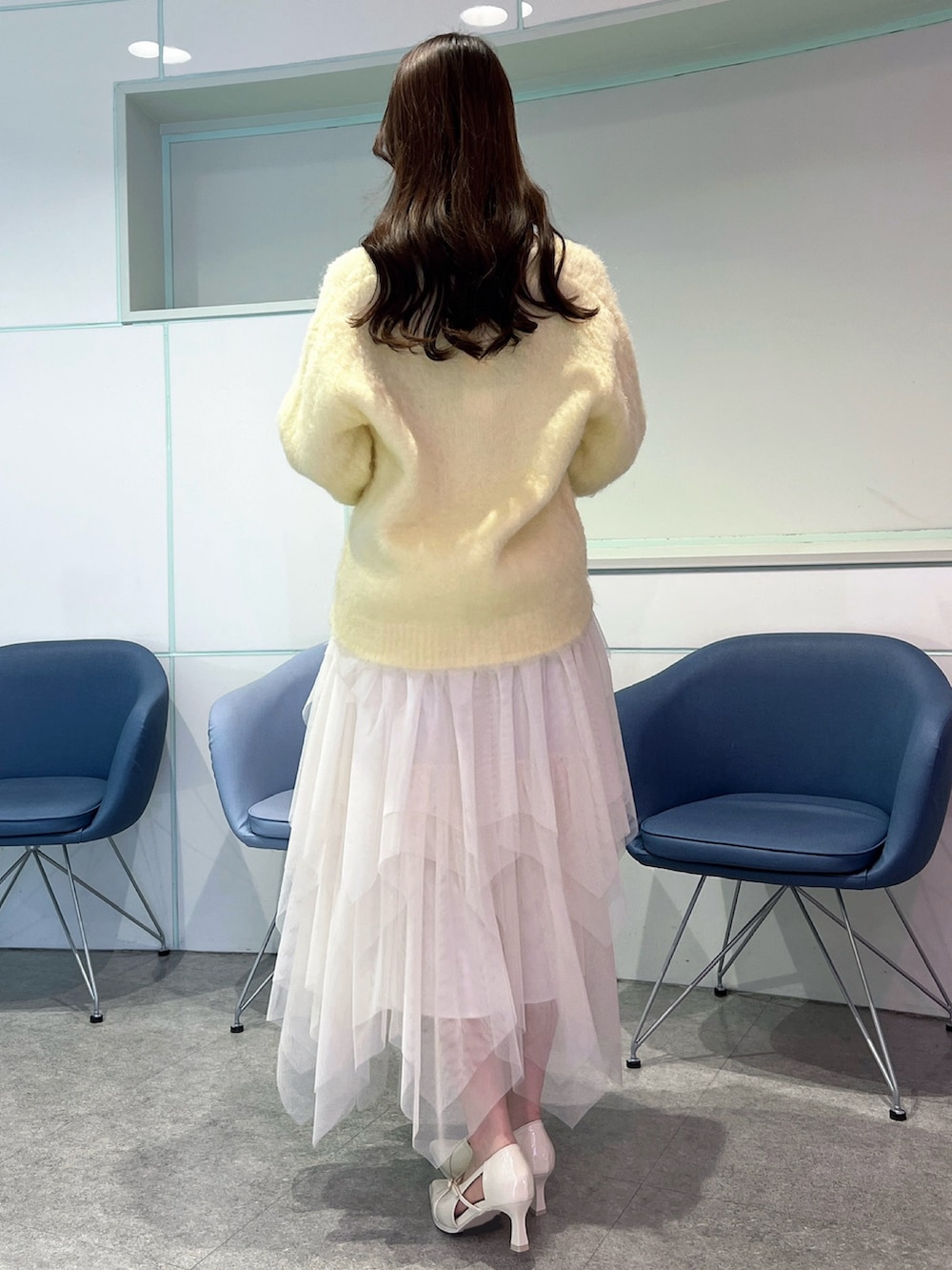 イエロー系のカーディガン/ボレロ、ホワイト系のスカート、ホワイト系のパンプスを着用したレディースの冬コーディネートの4枚目の写真