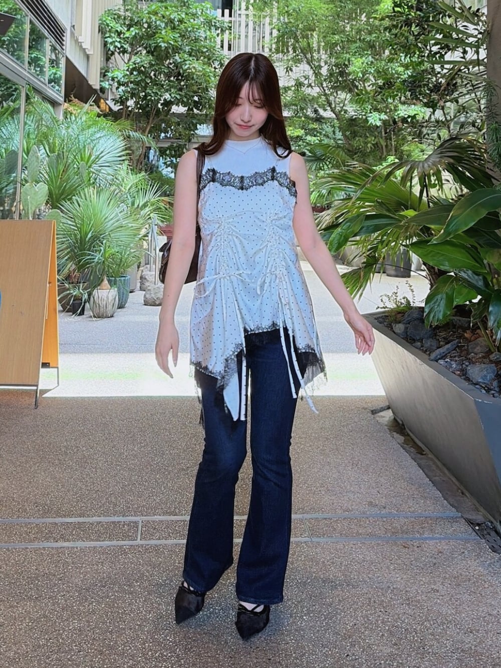 ブルー系のデニムパンツ、ブラック系のパンプス、ホワイト系のキャミソールを着用したレディースの夏コーディネートの2枚目の写真