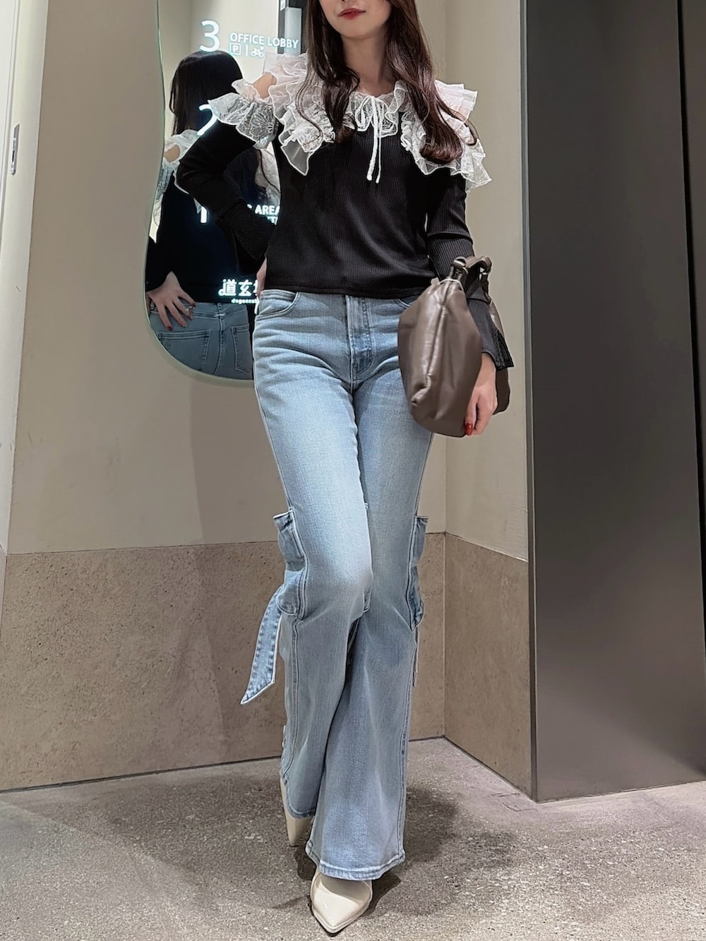 ブラック系のTシャツ/カットソー、ブルー系のデニムパンツ、ブラウン系のハンドバッグを着用したレディースの冬コーディネートの2枚目の写真