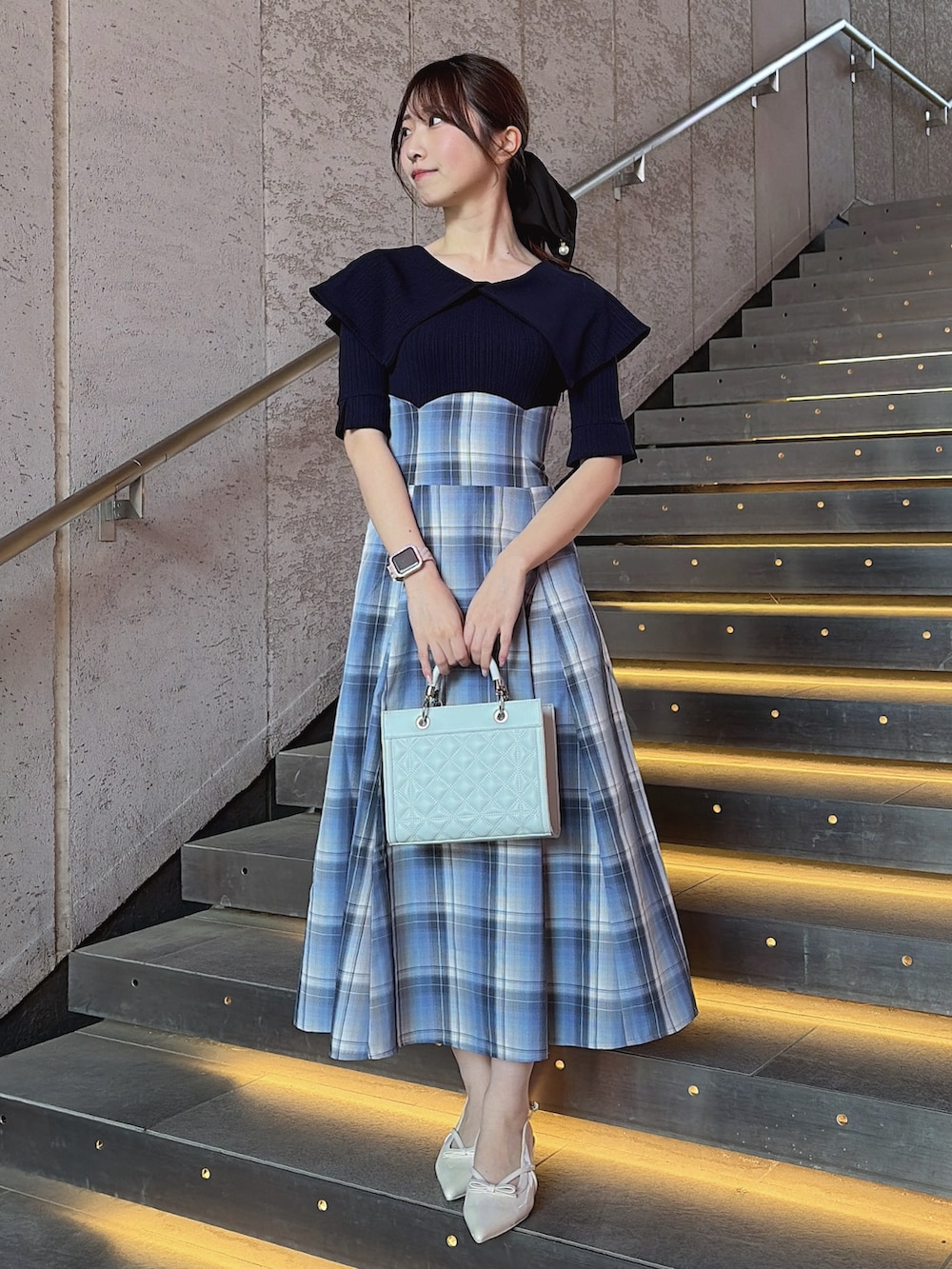 ブルー系のワンピース、ブルー系のハンドバッグ、ホワイト系のパンプスを着用したレディースの春コーディネートの2枚目の写真