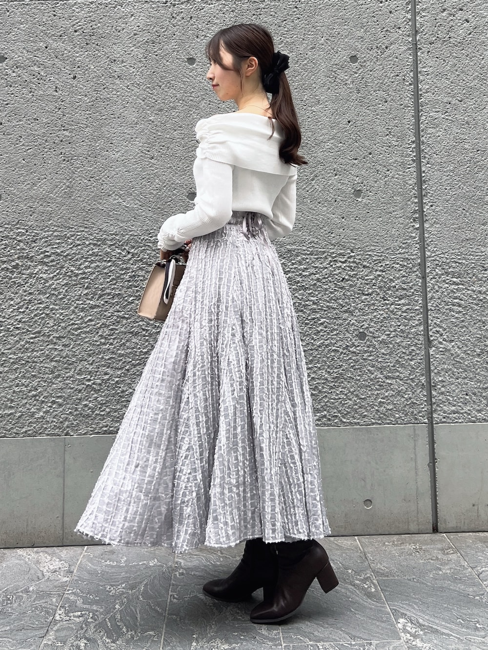 グレー系のスカート、ホワイト系のニット/セーター、ベージュ系のショルダーバッグを着用したレディースの秋コーディネートの3枚目の写真