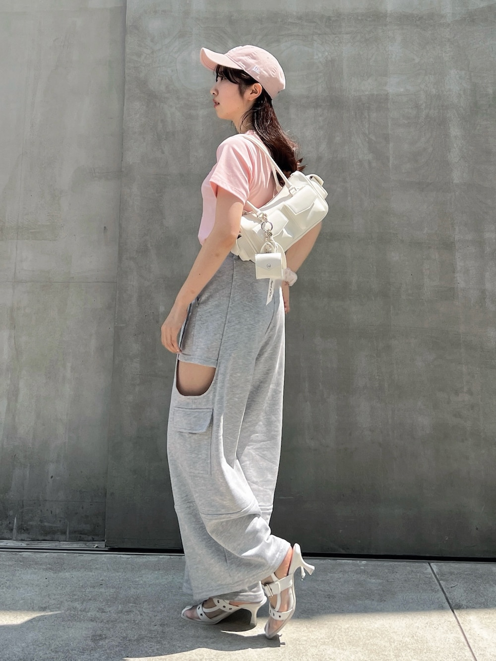 グレー系のカーゴパンツ、ピンク系のTシャツ/カットソー、ホワイト系のボストンバッグを着用したレディースの夏コーディネートの2枚目の写真