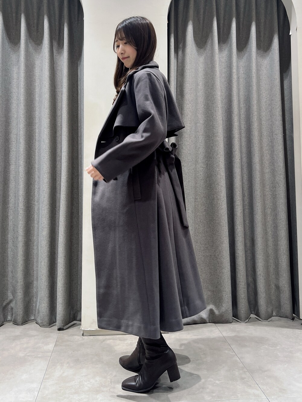 ブラウン系のトレンチコート、ブラウン系のブーツ、ホワイト系のスカートを着用したレディースの秋コーディネートの2枚目の写真