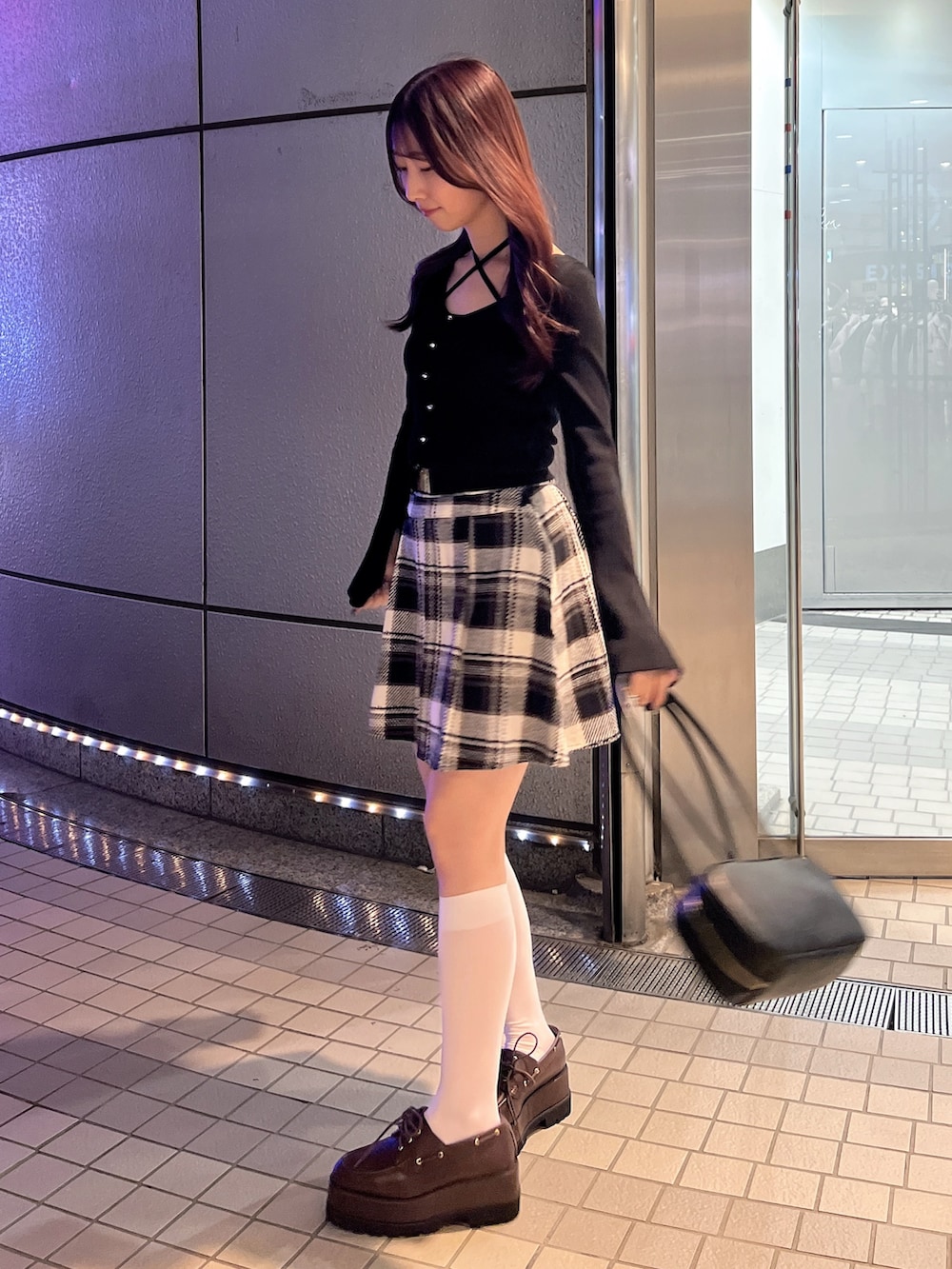 ブラック系のスカート、ブラック系のニット/セーター、ブラウン系のローファーを着用したレディースの冬コーディネートの3枚目の写真