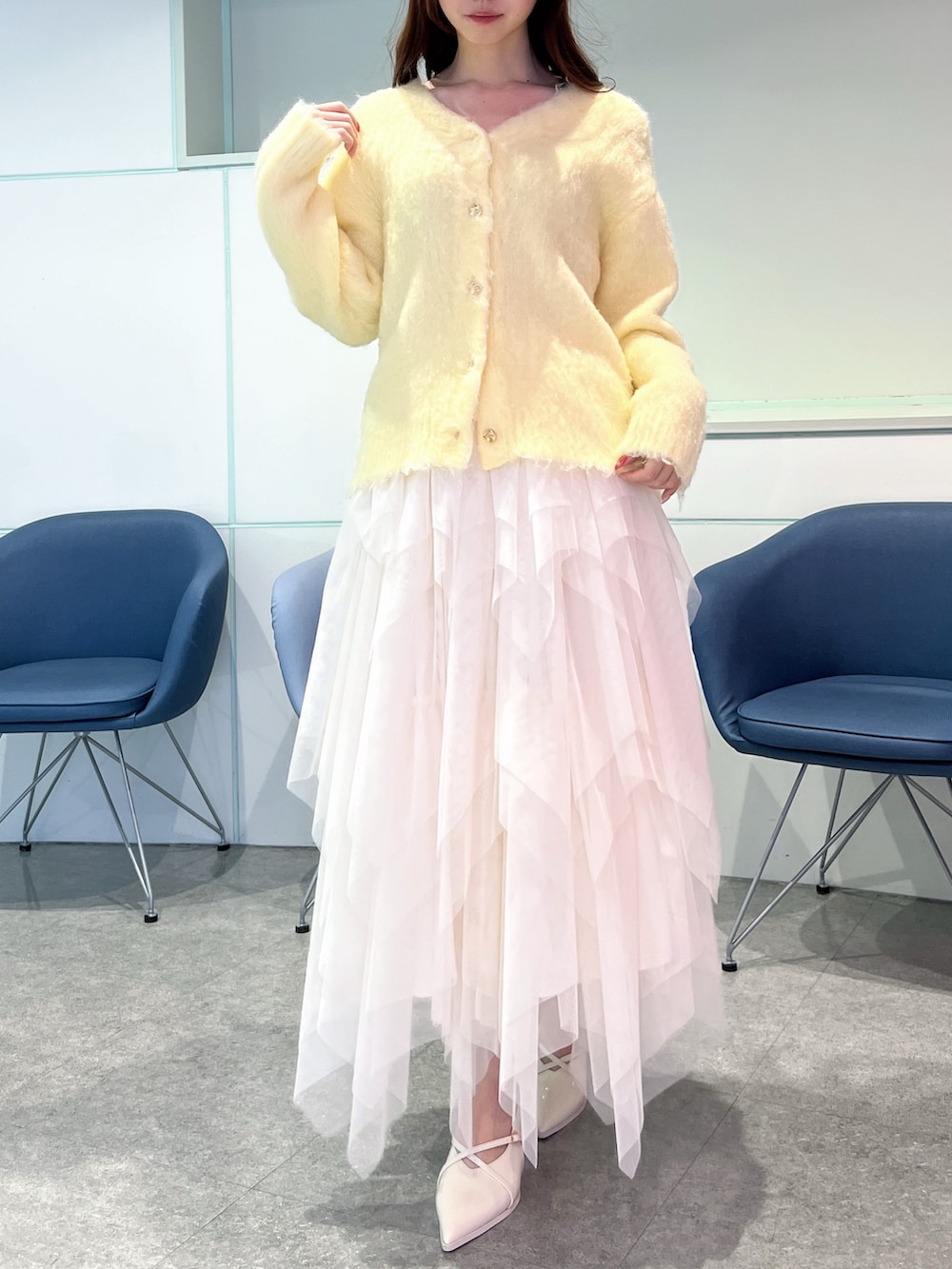 イエロー系のカーディガン/ボレロ、ホワイト系のスカート、ホワイト系のパンプスを着用したレディースの冬コーディネートの5枚目の写真