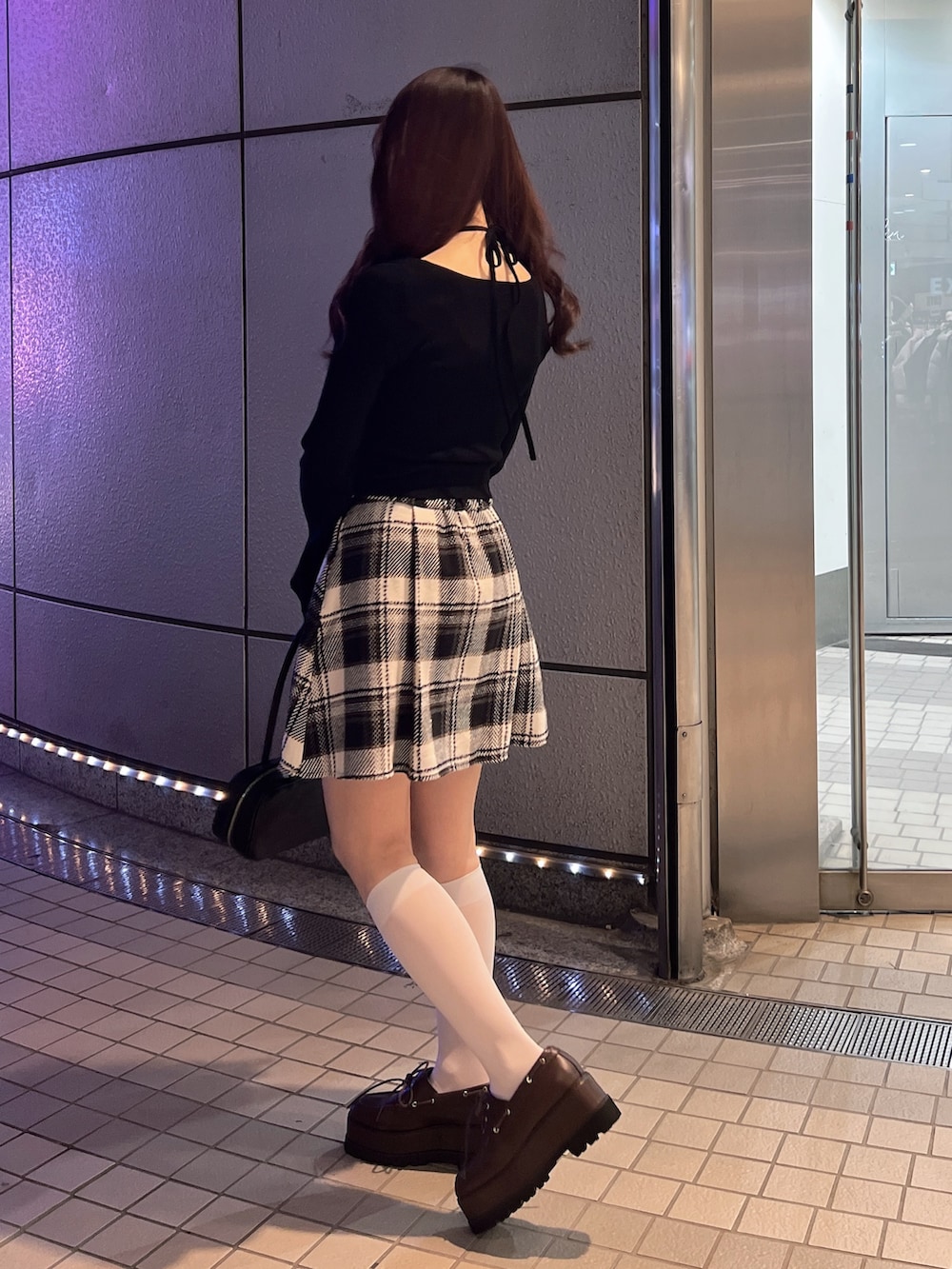 ブラック系のスカート、ブラック系のニット/セーター、ブラウン系のローファーを着用したレディースの冬コーディネートの4枚目の写真