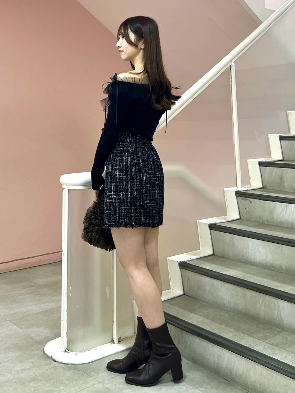 ブラック系のスカート、ブラック系のニット/セーター、ブラウン系のハンドバッグを着用したレディースの秋コーディネートの3枚目の写真