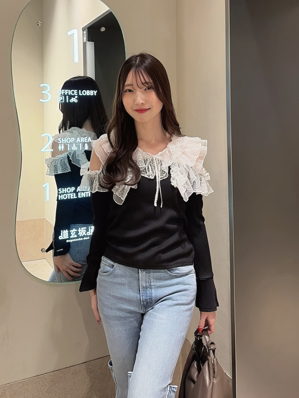 ブラック系のTシャツ/カットソー、ブルー系のデニムパンツ、ブラウン系のハンドバッグを着用したレディースの冬コーディネートの6枚目の写真