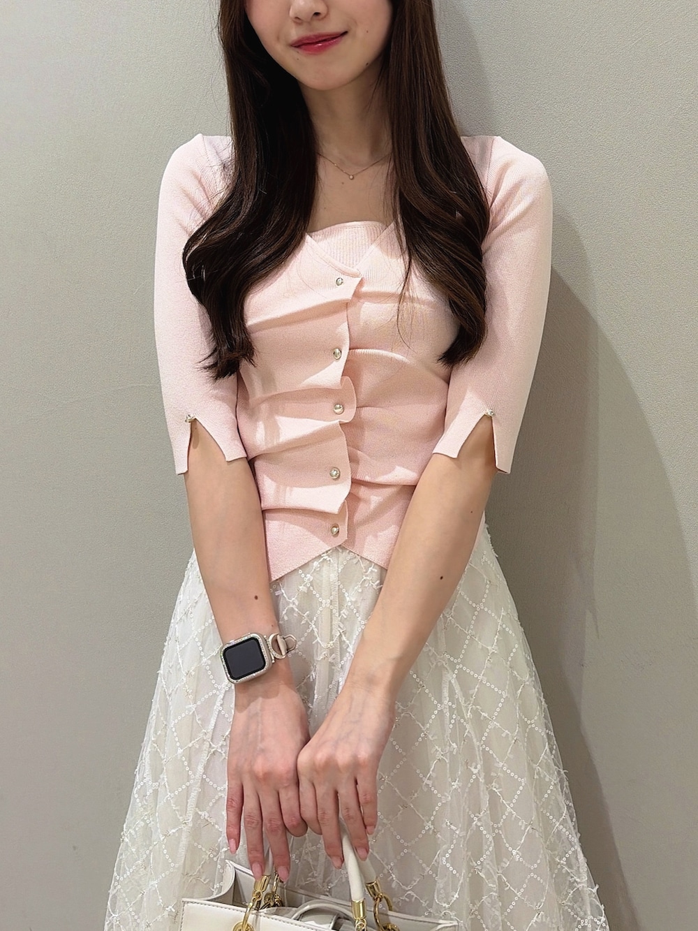 ホワイト系のパンプス、ホワイト系のハンドバッグ、ホワイト系のスカートを着用したレディースの夏コーディネートの7枚目の写真