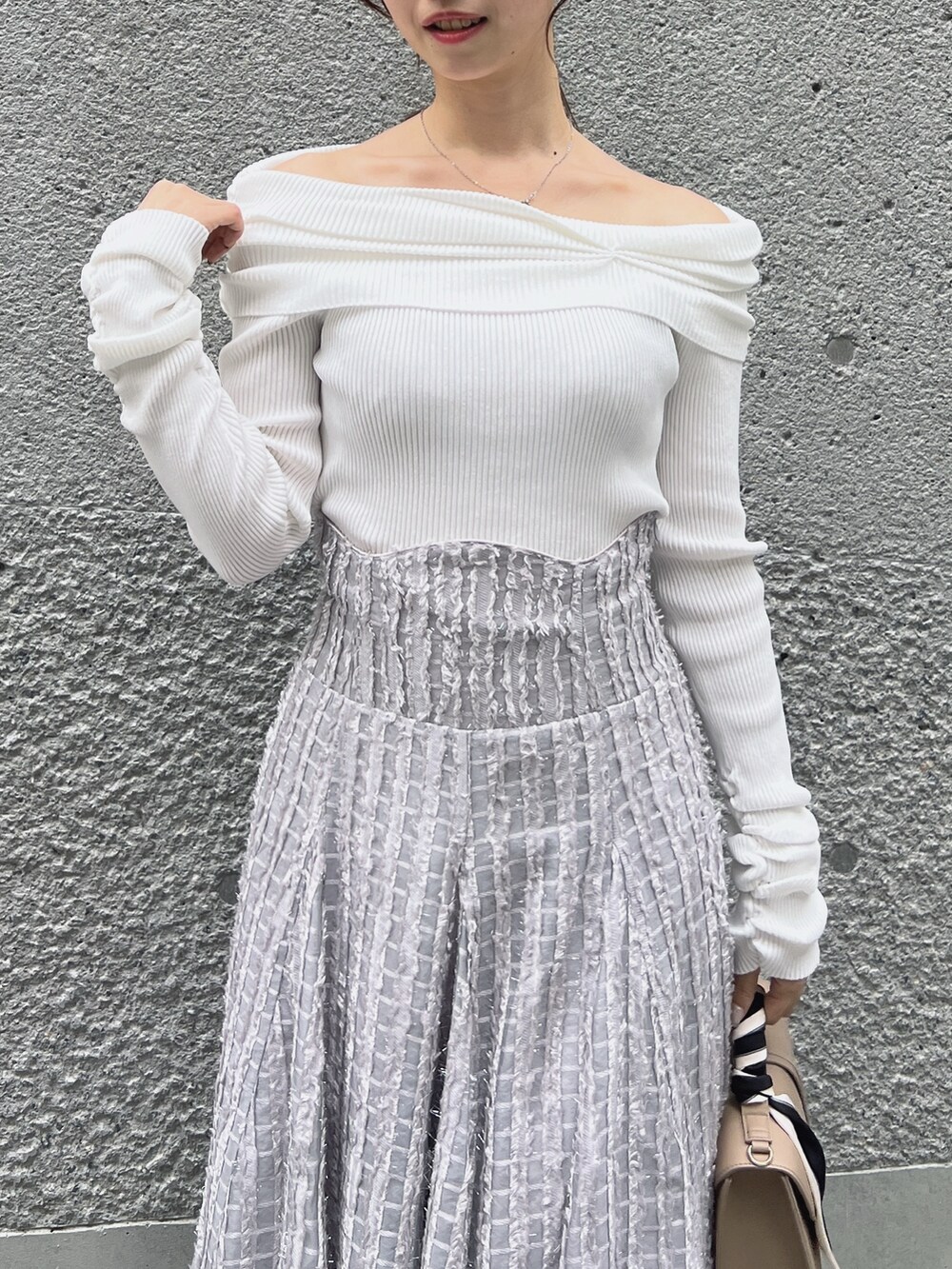 グレー系のスカート、ホワイト系のニット/セーター、ベージュ系のショルダーバッグを着用したレディースの秋コーディネートの5枚目の写真