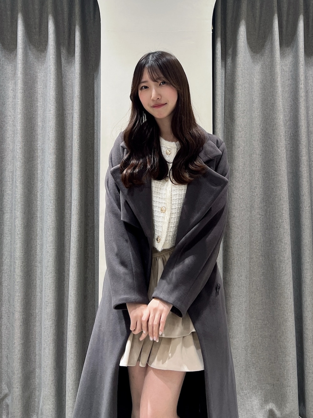 ブラウン系のトレンチコート、ブラウン系のブーツ、ホワイト系のスカートを着用したレディースの秋コーディネートの4枚目の写真