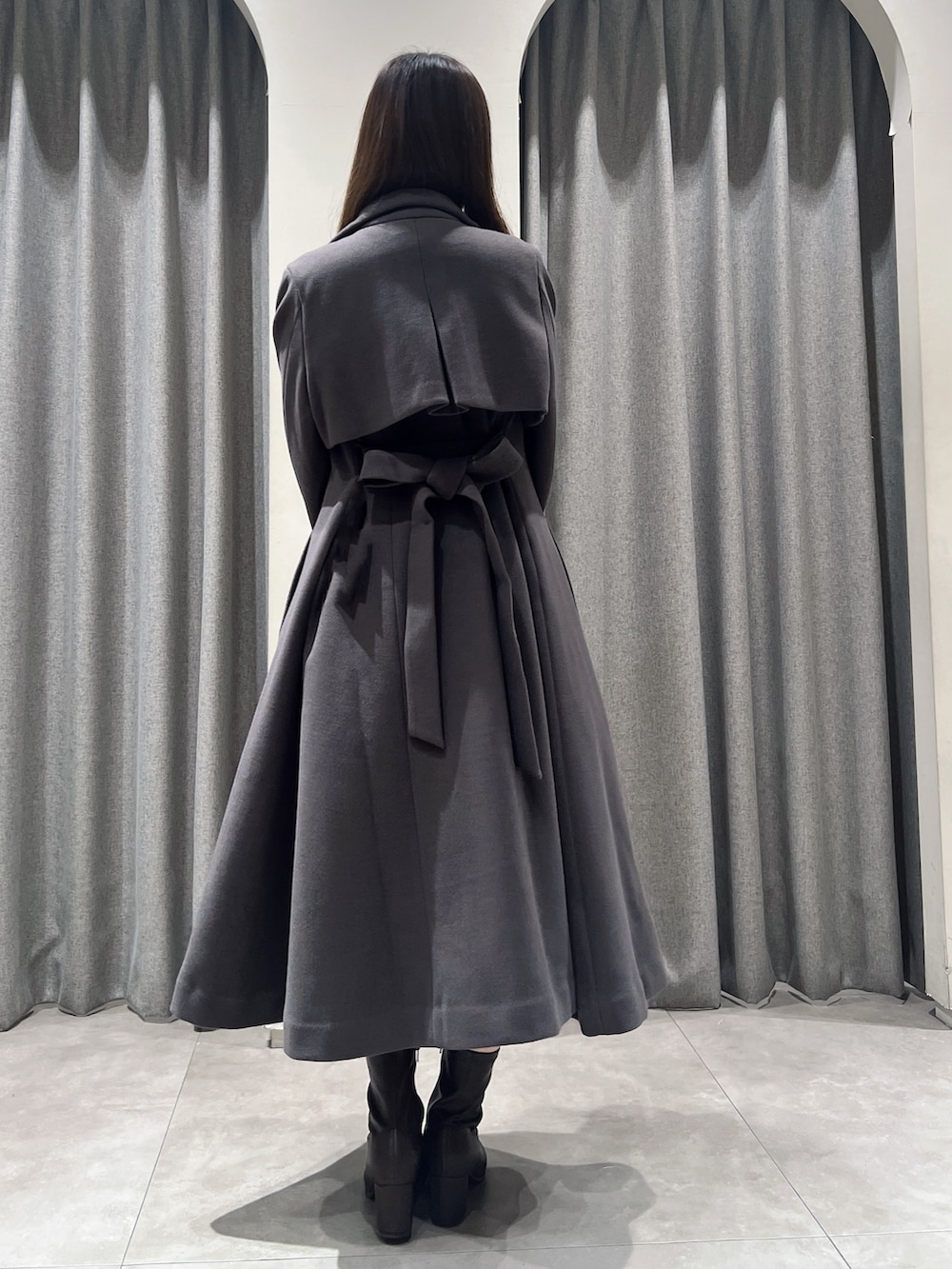 ブラウン系のトレンチコート、ブラウン系のブーツ、ホワイト系のスカートを着用したレディースの秋コーディネートの3枚目の写真