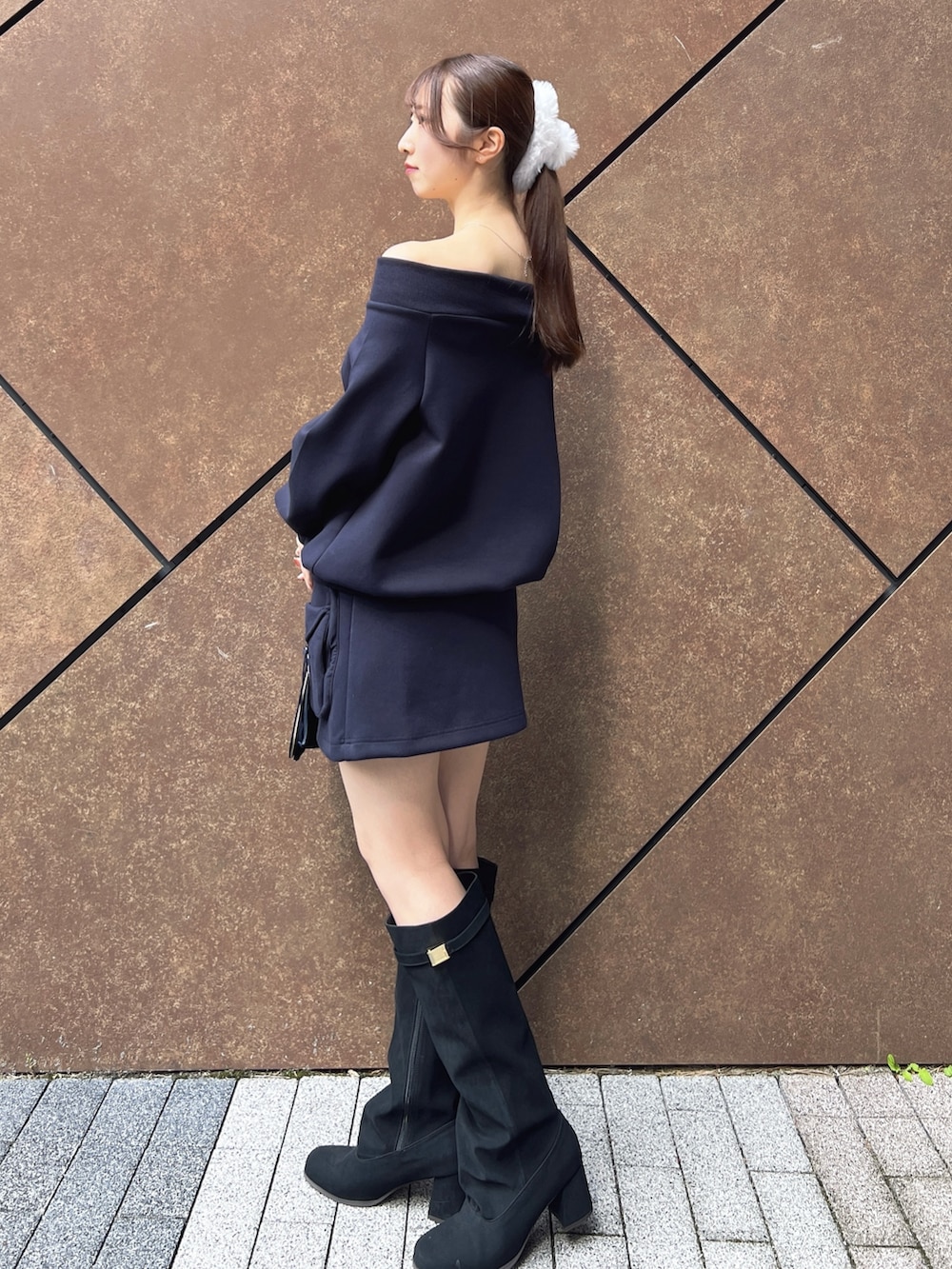 ブルー系のスウェット、ブルー系のスカート、ブラック系のハンドバッグを着用したレディースの秋コーディネートの3枚目の写真