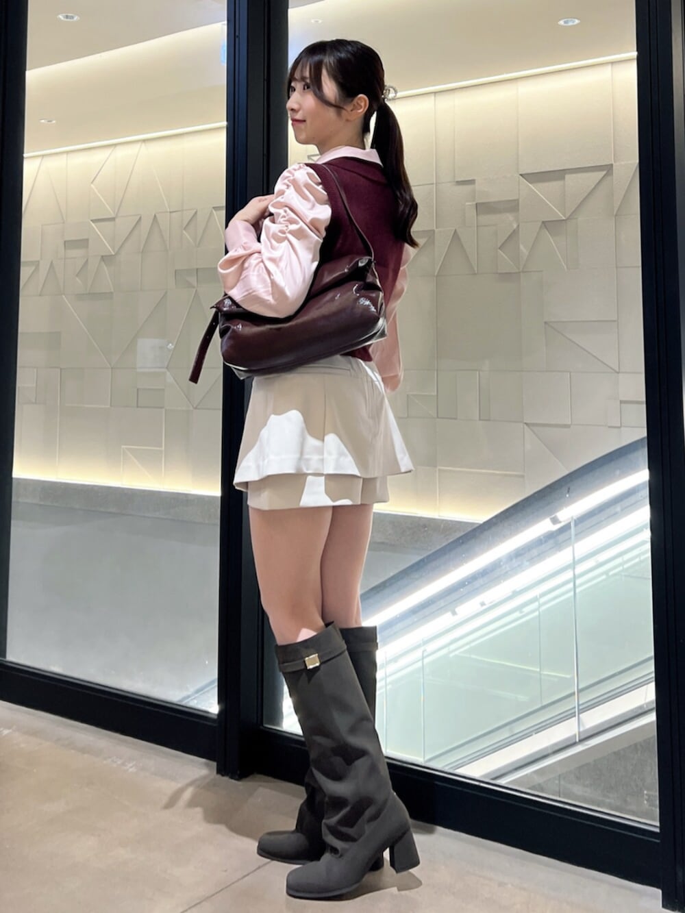 ブラウン系のブーツ、レッド系のハンドバッグ、ホワイト系のスカートを着用したレディースの秋コーディネートの2枚目の写真