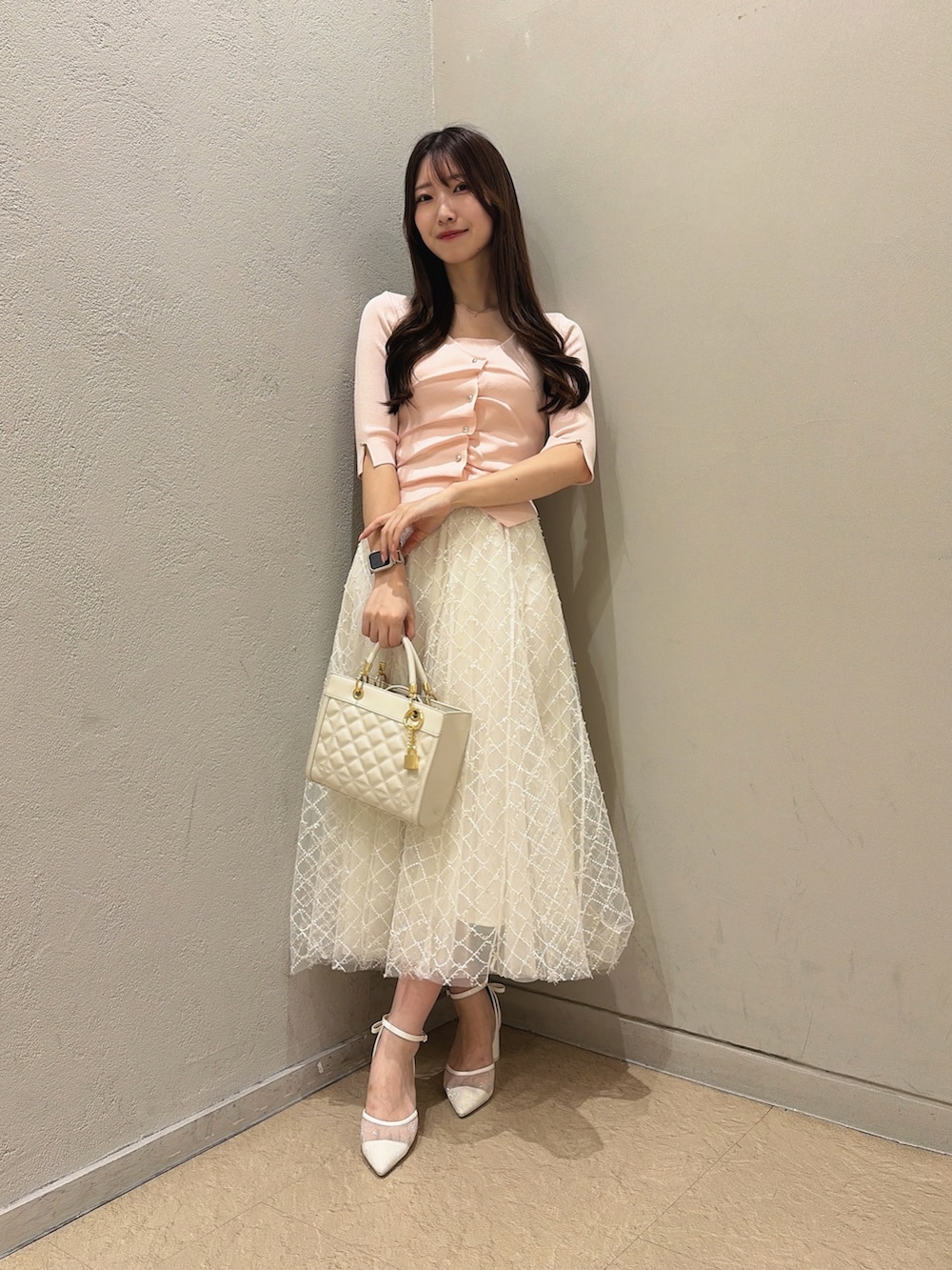 ホワイト系のパンプス、ホワイト系のハンドバッグ、ホワイト系のスカートを着用したレディースの夏コーディネートの5枚目の写真