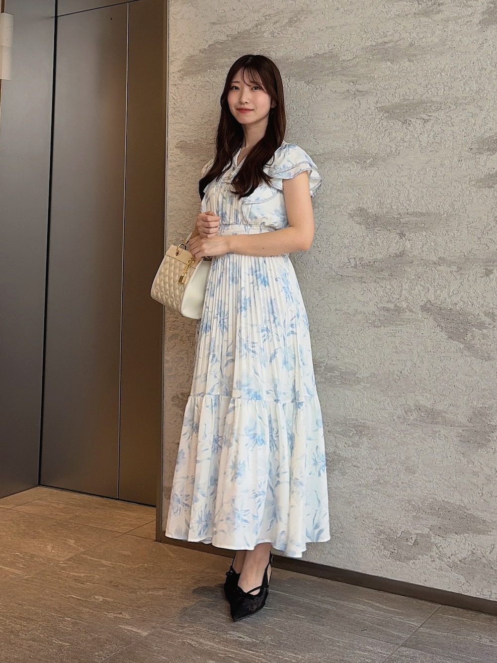 ブラック系のパンプス、ホワイト系のハンドバッグ、ブルー系のワンピースを着用したレディースの夏コーディネートの4枚目の写真