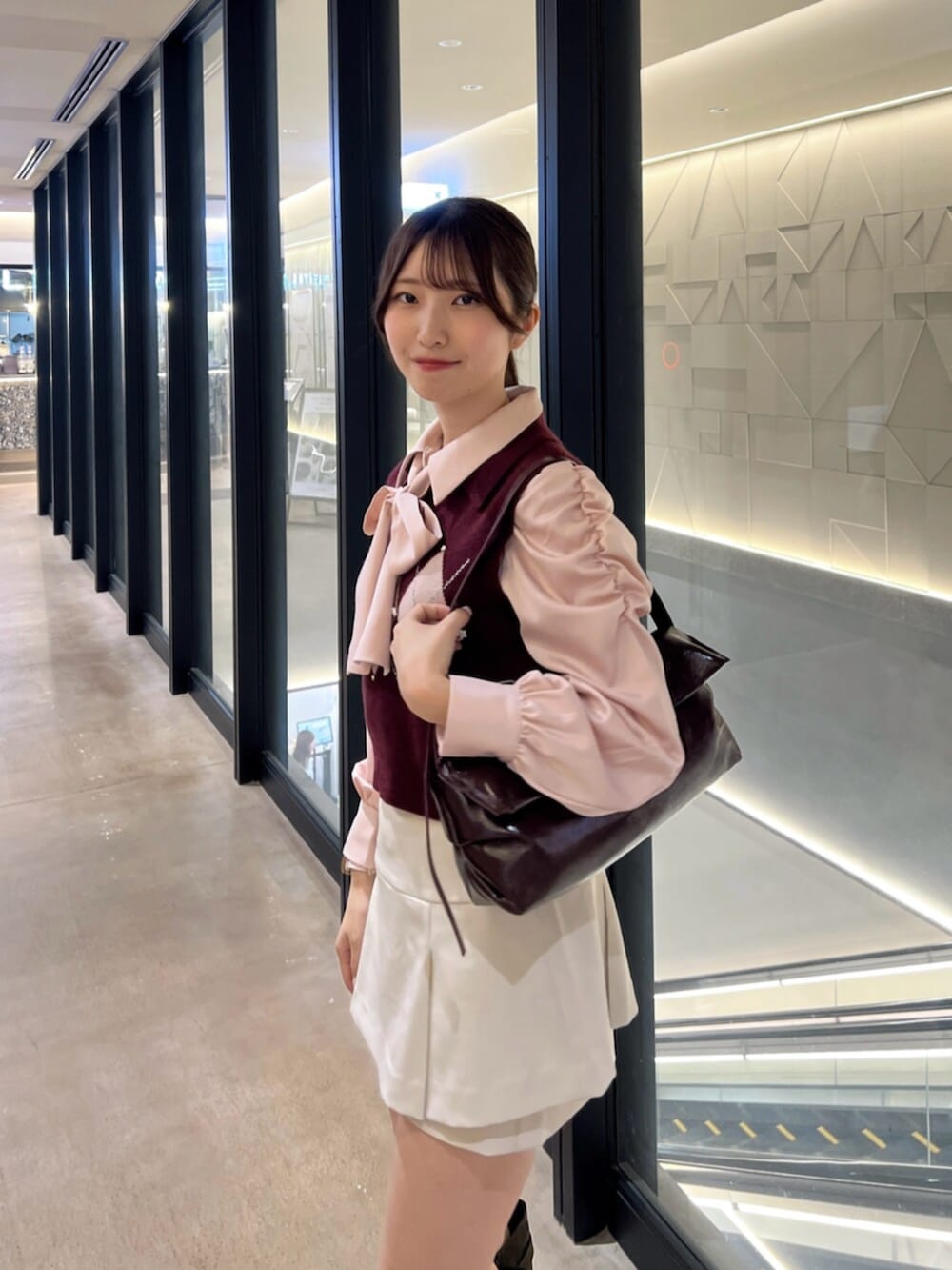 ブラウン系のブーツ、レッド系のハンドバッグ、ホワイト系のスカートを着用したレディースの秋コーディネートの5枚目の写真