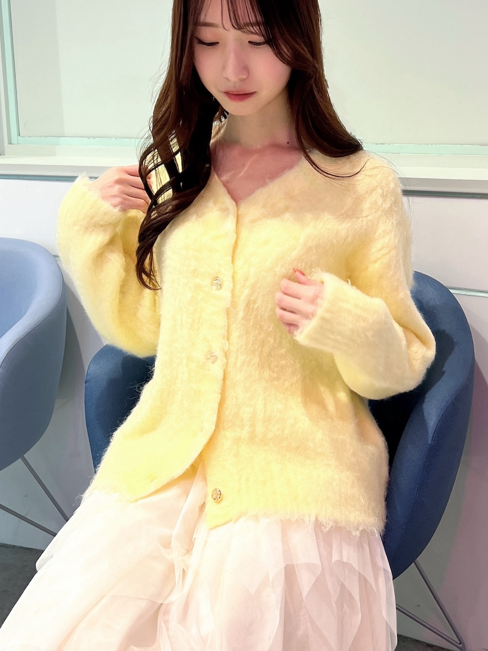 イエロー系のカーディガン/ボレロ、ホワイト系のスカート、ホワイト系のパンプスを着用したレディースの冬コーディネートの6枚目の写真