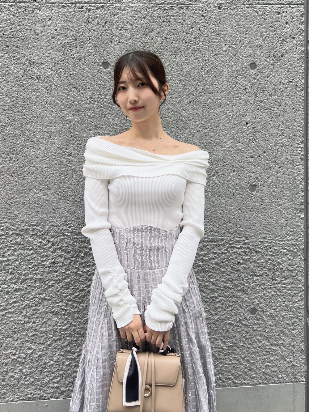 グレー系のスカート、ホワイト系のニット/セーター、ベージュ系のショルダーバッグを着用したレディースの秋コーディネートの6枚目の写真